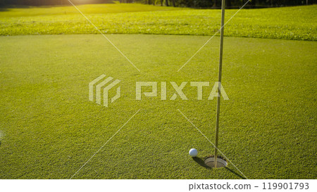 Golf ball on green grass in the evening golf course with sunshine background. 119901793