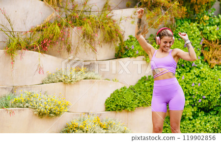 An Energetic Young Woman is Joyfully Dancing Outdoors in Colorful Fitness Attire An Energetic Young Woman is Joyfully Dancing Outdoors in Colorful Fitness Attire 119902856