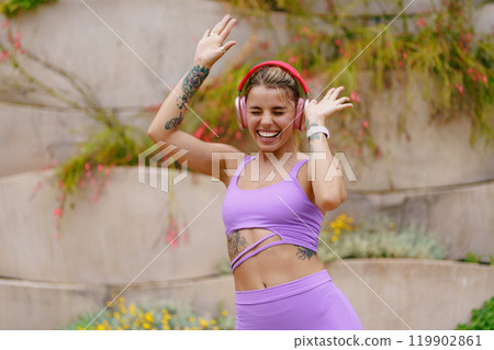 A Joyful Woman Dancing Outdoors while Wearing Headphones, Embracing Lifes Vibrancy and Energy A Joyful Woman Dancing Outdoors while Wearing Headphones, Embracing Lifes Vibrancy and Energy 119902861