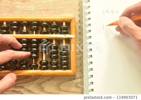 hand used wooden abacus old Chinese tool for calcuated and note in book on working desk 119903071