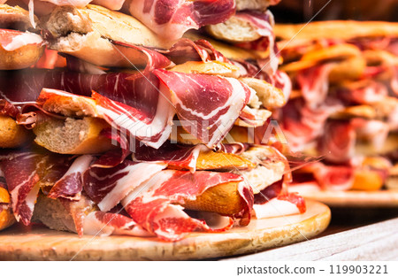 Traditional Spanish bocadillos with Iberico jamon laid out in a slide on a shop window 119903221