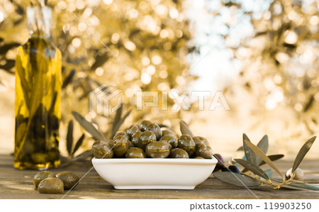 Green olives and oil on table in olive grove Green olives and oil on table in olive grove 119903250