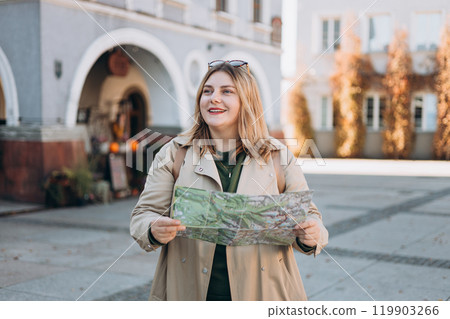 Happy young woman with map in old town. Holidays and tourism concept. Female tourist searching direction on location map while traveling abroad in autumn 119903266