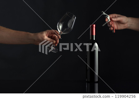Bottle of red wine and hands with corkscrew and wine glass. Bottle of red wine and hands with corkscrew and wine glass. 119904256