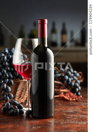 Bottle and glass of red wine with grapes on a vintage table. 119904284