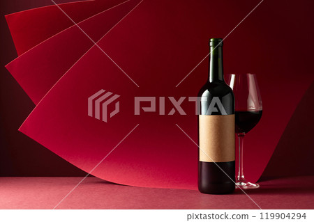 Bottle and glass of red wine on a red background. 119904294