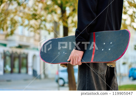 Skateboarder holding worn pink skateboard at street Skateboarder holding worn pink skateboard at street 119905047