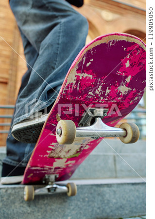 Close-up of skateboarder on pink skateboard at street 119905050