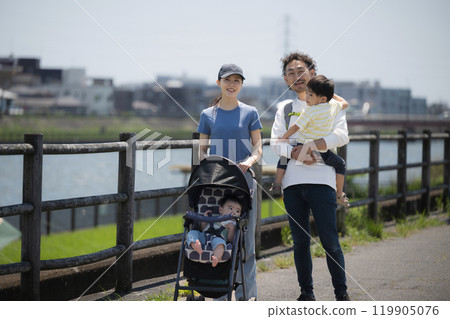 Full body of a parent and child (family of four) walking in a park along a river on a sunny day. Image of spring/summer outings and leisure activities. Wide-angle 119905076