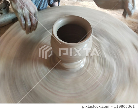 Artisan potter creating a clay vase on a wheel in a modern workshop. "A talented potter is molding a clay vase on a pottery wheel 119905361
