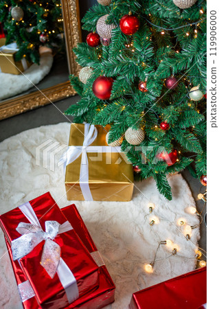Gifts under Christmas tree with red, gold and silver toys. Festively decorated Christmas tree with garlands. Symbol of the new year in traditional colors Gifts under Christmas tree with red, gold and silver toys. Festively decorated Christmas tree with garlands. Symbol of the new year in traditional colors 119906000