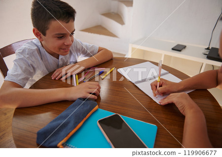 Boy and adult writing together at a table with school supplies Boy and adult writing together at a table with school supplies 119906677