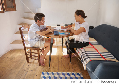 Mother helping son with homework at home in cozy setting 119906685