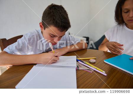 Young boy focused on doing homework with parental support 119906698