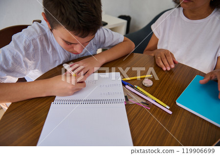 Young boy receiving guidance for his homework at the table 119906699