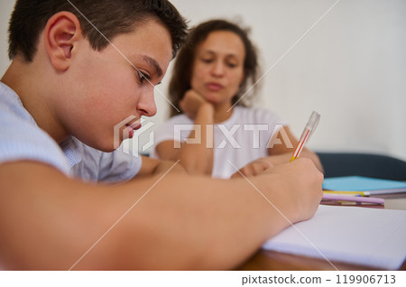 Focused student diligently working under tutor's supervision at home 119906713