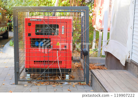 Generator uses a cafe with an outdoor terrace in autumn. Outdoor diesel power generator. Power supply generator placed on street sidewalk. Generator uses a cafe with an outdoor terrace in autumn. Outdoor diesel power generator. Power supply generator placed on street sidewalk. 119907222