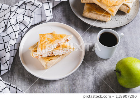 Cottage cheese and apple wrapped in fried lavash on a plate on the table 119907290