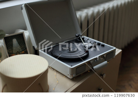 a vintage vinyl record player elegantly positioned on a rustic wooden table. a sense of nostalgia and appreciation for the analog sound, inviting viewers to immerse themselves in the world of classic 119907630