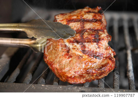 Cooking steak on the grill and coals. Roasting steak in a restaurant. 119907787