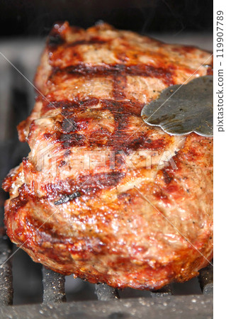 Cooking steak on the grill and coals. Roasting steak in a restaurant. 119907789