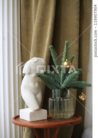 a stylish side table adorned with a striking statue and an array of festive decorations 119907904