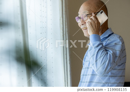 Senior man making a phone call while looking outside 119908135