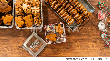 Lovingly homemade gingerbread and sugar cookies, half-dipped in rich chocolate, nestled in decorative Christmas tin boxes perfect for seasonal gifting. 119908154