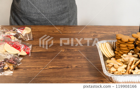 Carefully packaging Christmas cutout cookies, half-dipped in chocolate and presented in clear cellophane wrapping, perfect for festive gifting. Carefully packaging Christmas cutout cookies, half-dipped in chocolate and presented in clear cellophane wrapping, perfect for festive gifting. 119908166