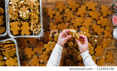 Flat lay. Crafting gingerbread cookie sandwiches with eggnog buttercream, presented on a rustic wooden table for Christmas gifting. 119908196