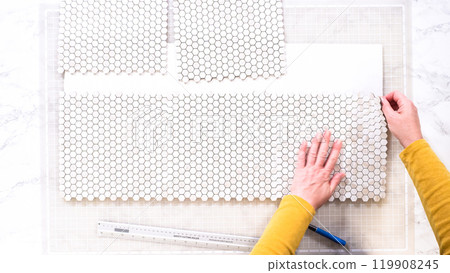 Flat lay. In the process of mounting peel and stick mosaic tiles onto a foam board, perfect for enhancing a food photography studio's aesthetic. 119908245