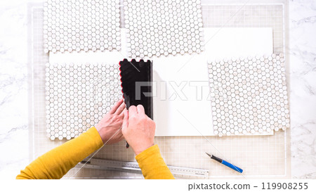 Flat lay. In the process of mounting peel and stick mosaic tiles onto a foam board, perfect for enhancing a food photography studio's aesthetic. 119908255