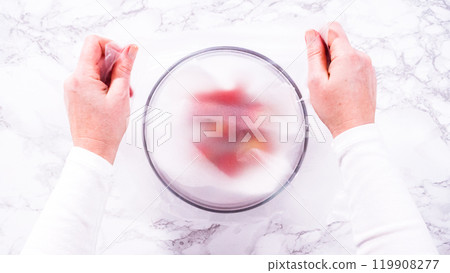 Flat lay. Strawberries, freshly washed and dried, are neatly stored in a glass bowl lined with a paper towel and securely covered with plastic wrap to maintain freshness. 119908277