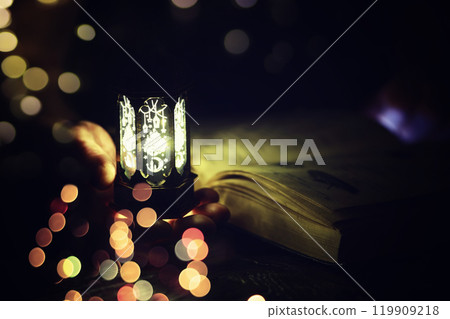 Ramadan Kareem background. Ornamental Arabic lantern glowing and the holy book of Quran. 119909218