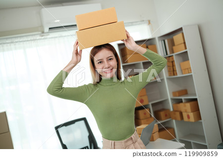A woman wearing a green shirt is holding two boxes on her head 119909859