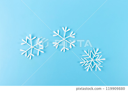 Snowflake made from cotton swabs hanging on string against blue background. Minimalist winter decoration. Christmas and winter holidays concept 119909880