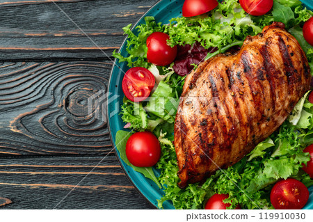 Grilled chicken breast ( fillet ) with lattuce salad and cherry tomatoes . Top view Grilled chicken breast ( fillet ) with lattuce salad and cherry tomatoes . Top view 119910030