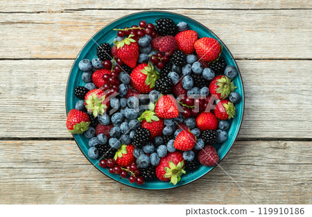 Mix of ripe colorful berries in bowl photography . Blueberry , strawberry , raspberry , blackberry and red currant . Top view 119910186