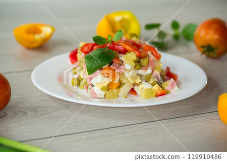 vegetable salad of boiled vegetables, with peas, sausage, sweet pepper. On a wooden table vegetable salad of boiled vegetables, with peas, sausage, sweet pepper. On a wooden table 119910486