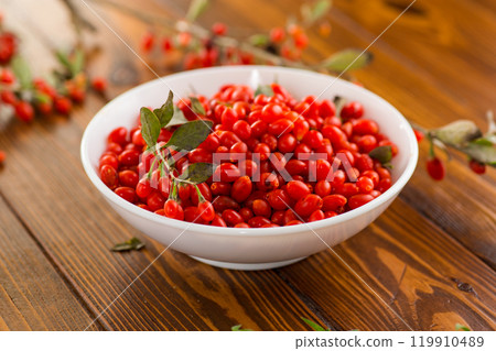 fresh ripe red goji berries in a bowl on a wooden table 119910489
