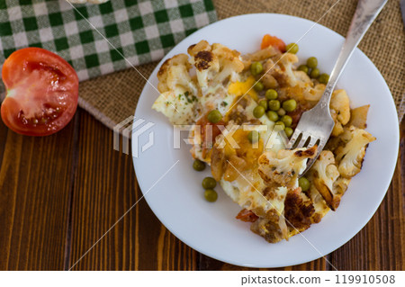 fried omelette with cauliflower and vegetables in a plate on a wooden table 119910508