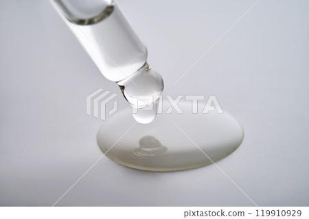 Dropper pipette with delicious serum with drop close-up. Dropper pipette with delicious serum with drop close-up. 119910929
