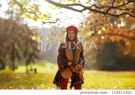 happy trendy 40 years old woman throwing autumn leafs 119911402