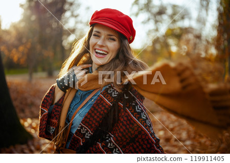 smiling young woman in red hat with scarf in city park smiling young woman in red hat with scarf in city park 119911405