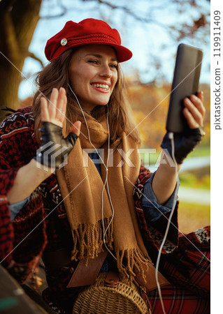 happy woman talking call while sitting on bench in city park 119911409