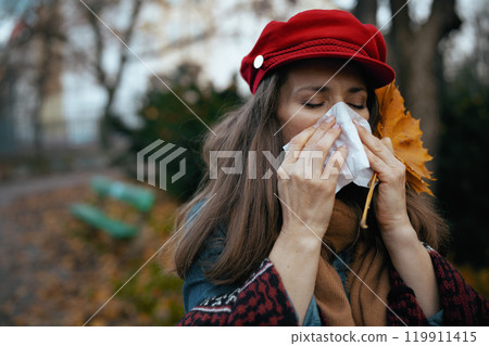 stylish 40 years old woman in red hat blowing nose 119911415