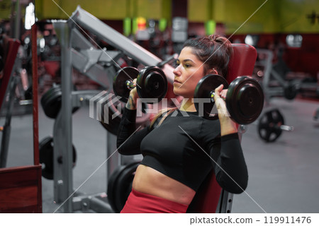 Young Woman Training shoulders With Dumbbells At The Gym. 119911476