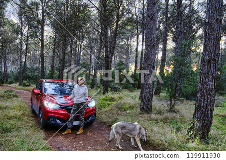 Car and adult woman lost in wooded area trying to orient herself at dusk. Car and adult woman lost in wooded area trying to orient herself at dusk. 119911930