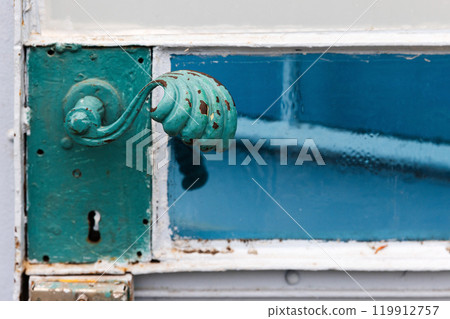 Vintage green forged handle of a metal door 119912757