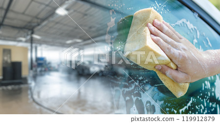 A hand with a washcloth washes a car window. A hand with a washcloth washes a car window. 119912879